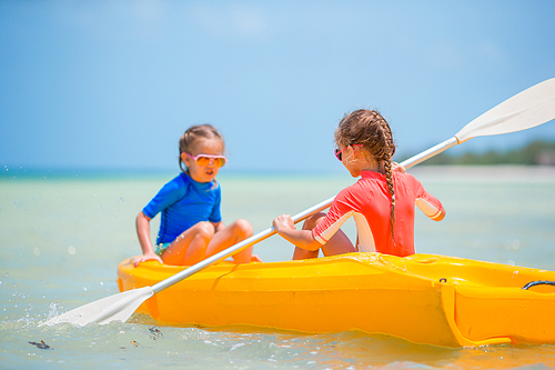 Little active girls kayaking in the sea on yellow kayak