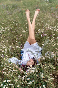 Long female legs are raised up in the field. A beautiful woman lies on her back in a field and lifts up her beautiful legs. Good morning.
