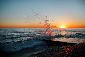 Seascape with waves on the beach against a sunset, splashes and drops