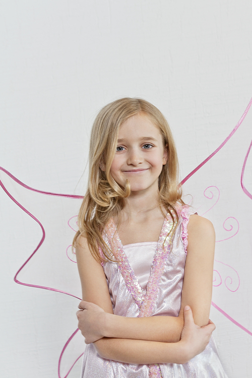 Portrait of a happy young girl with arms crossed over colored background