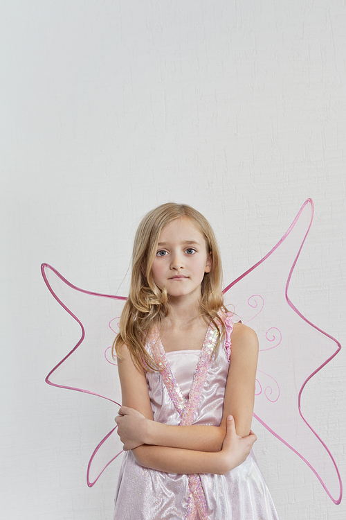 Portrait of a young girl with arms crossed over colored background