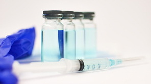 Vial vaccine, glass ampoules and a syringe with medical protective gloves on white background, global vaccination concept.