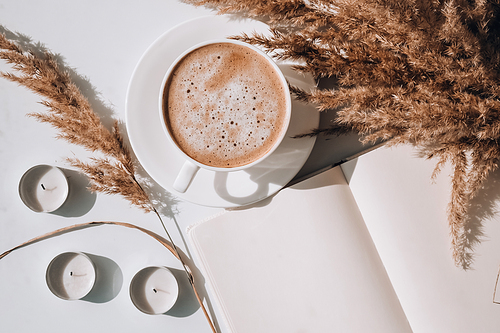 pampas grass and white cup with coffee. empty notebook making a plan for the day.  cappuccino in the breakfast morning at home. flat lay. wallpaper. aesthetics cozy home