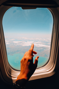 Female hand Airplane flight. View from the window of the plane. Airplane, Aircraft. Vacation travel concept Traveling by air. Airplane Window View Above the Clouds Amazing golden fluffy clouds moving softly on the sky aerial view.