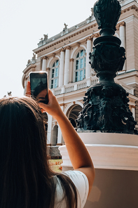 Young woman taking photo of National Odessa National Academic Opera and Ballet Theatre. Traveler Architectural monument. Travel destination. Vacation Concept Exterior Art building
