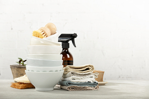 Zero waste home kitchen cleaning concept, front view of dishes, dish washing brushes, organic soap bar, kitchen towels, house plant and eco safe all purpose cleaner in reused glass jar, blank space for a text