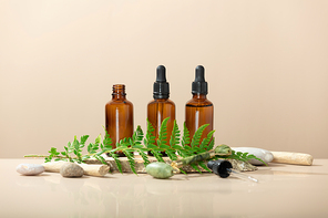 Amber glass transparent bottles on wooden podium with Jade face roller, leaves and natural stones. Natural organic cosmetic packaging, luxury beauty products for anti age face massage