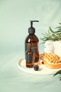 Amber glass bottles with wooden massage brush, eucalyptus leaves and towels. Natural organic eco cosmetic packaging, luxury beauty products for body care