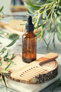 Amber glass transparent bottle with eucalyptus leaves and wooden hair brush. Natural organic cosmetic packaging, luxury beauty products for hair care