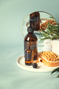 Amber glass bottles with wooden massage brush, eucalyptus leaves, mirror and towels. Natural organic eco cosmetic packaging, luxury beauty products for body care