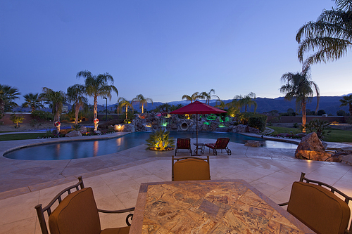 Swimming pool with chaise lounge outside mansion at dusk