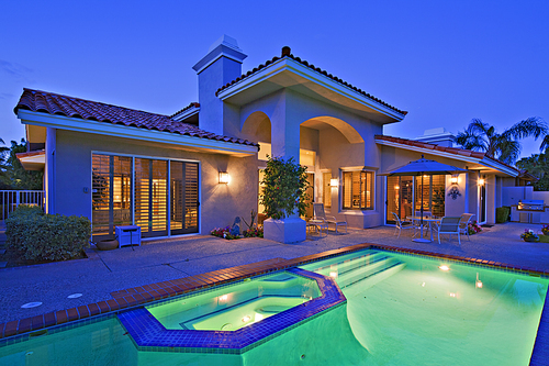 Illuminated swimming pool with Jacuzzi in front of luxury mansion