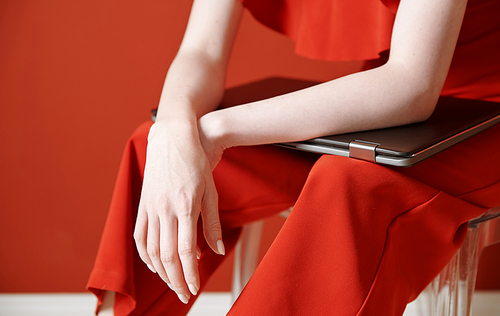 Young adult woman sitting on a chair and holding laptop