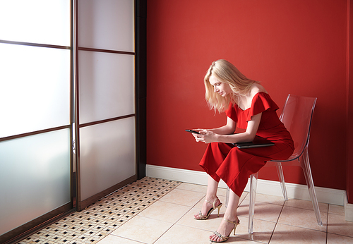 Young adult woman using smartphone and holding laptop