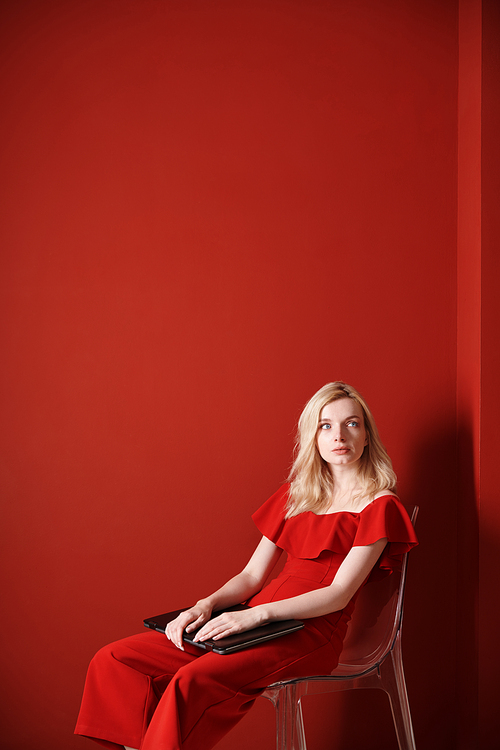 Young adult woman sitting on a chair and holding laptop