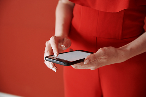 Young adult woman using smartphone next to the red wall