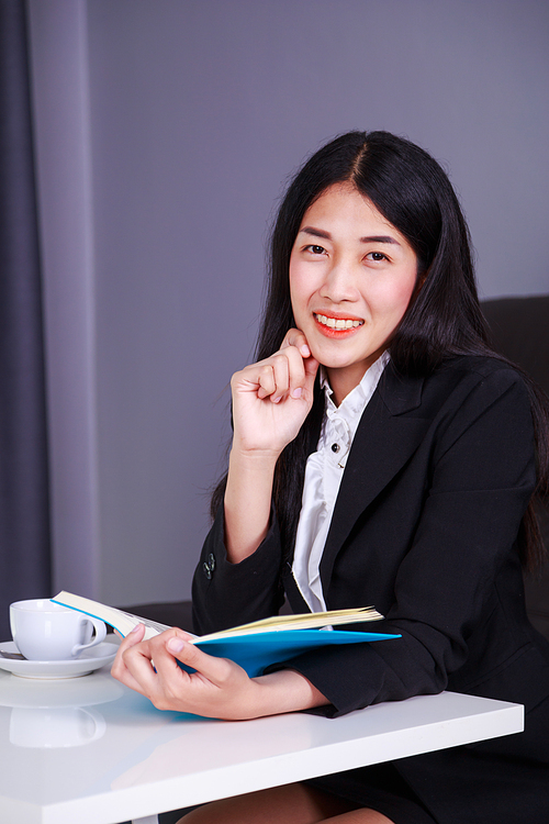 happy young business woman sitting at the desk and holding a book