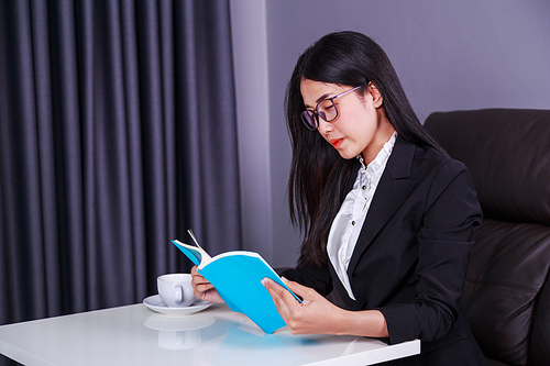 young business woman sitting at the desk and reading a book