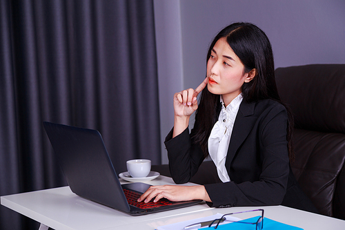 young business woman sitting at the desk with laptop and thinking