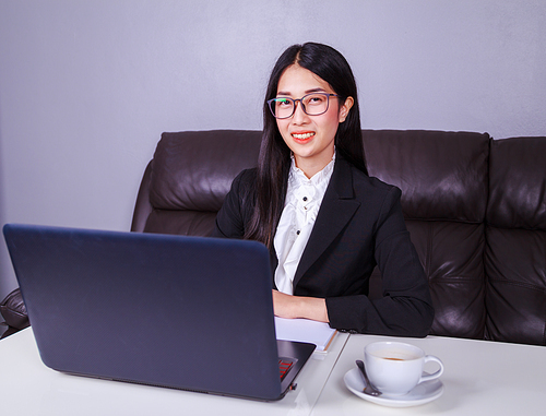 happy young business woman sitting at the desk and using laptop computer for her work