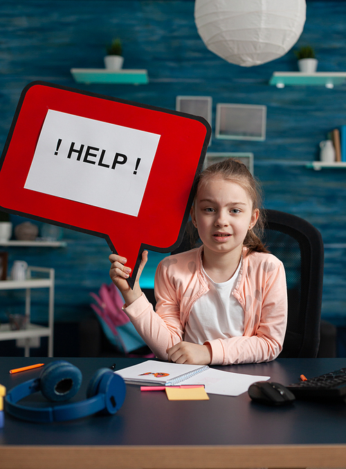 Conceptual image of elementary school kid with sign asking for help with assignments and homework for online internet classes and lessons. Small caucasian girl having creativity