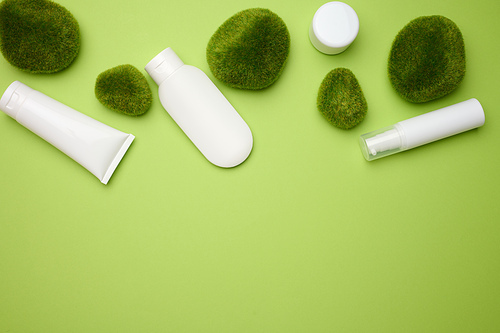 jar, bottle and empty white plastic tubes for cosmetics on a green background. Packaging for cream, gel, serum, advertising and product promotion, mock up