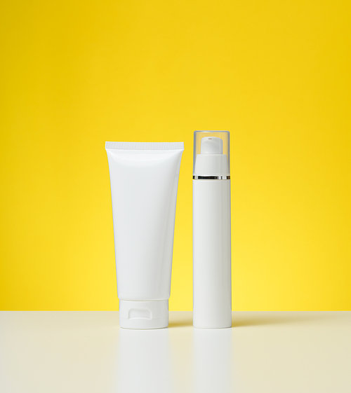 plastic white bottle with a dispenser and a tube with a lid on a white table, yellow background. Packaging for cosmetics, branding and product promotion