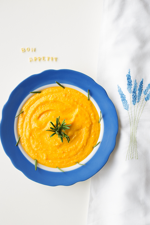 pumpkin soup in a blue plate on a napkin with flowers