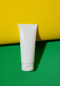 empty white plastic tubes for cosmetics on a green yellow background. Packaging for cream, gel, serum, advertising and product promotion, mock up