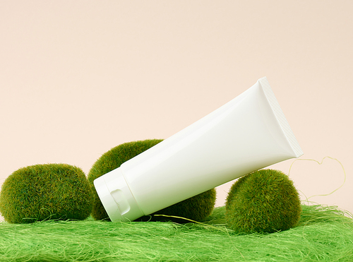 empty white plastic tubes for cosmetics on a green background. Packaging for cream, gel, serum, advertising and product promotion, mock up