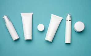 jar, bottle and empty white plastic tubes for cosmetics on a blue background. Packaging for cream, gel, serum, advertising and product promotion, mock up