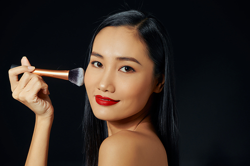 Beautiful Young Asian Woman using Soft Brush and Cosmetic on own face.