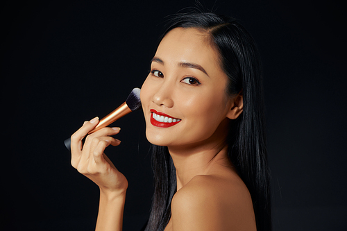 Beautiful Young Asian Woman using Soft Brush and Cosmetic on own face.