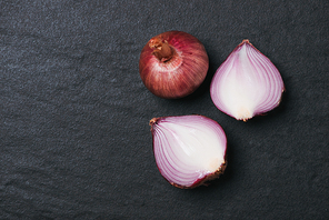 Full and half cut spanish onions on dark background.
