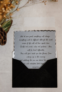 wedding invitation in a gray envelope on a table with green sprigs