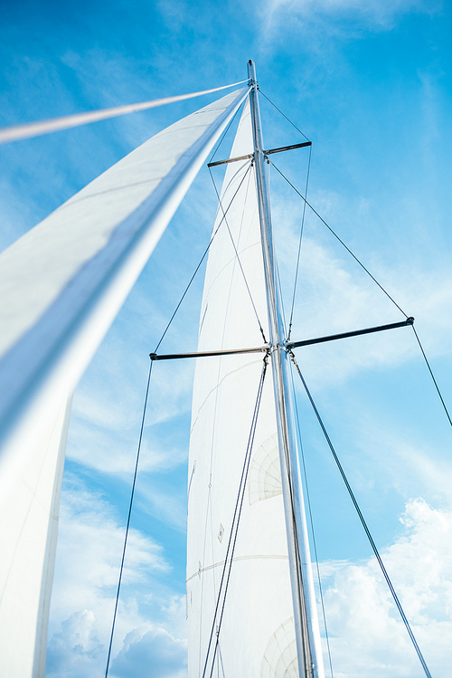 high mast with a white sail against the blue sky