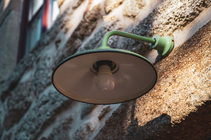 Green ld industrial style lamp on granite wall.