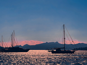 Tranquil seascape and coastal nature concept. Sea, boats, mountains and blue sky over horizon at sunset.