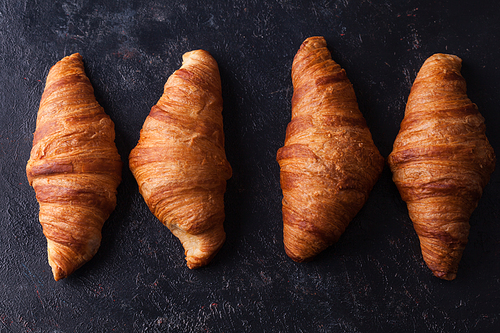 Fresh baked traditional croissants on dark wooden table. Morning snack.