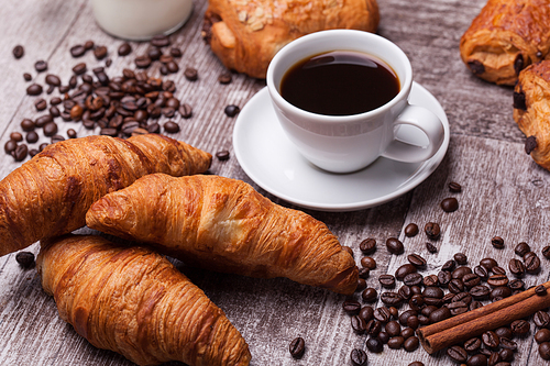 Coffee and croissant for breakfast on rustic wooden table. Tasty food.
