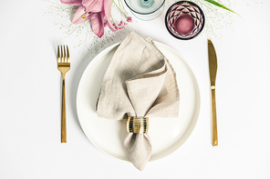 Elegant table setting with floral decor, flat lay. Wedding or festive table setting. Plate and cutlery with pink flowers on white background