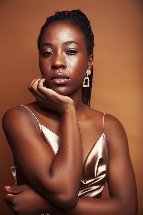 pretty young african american woman with braids posing cheerful gesturing on brown background, lifestyle people concept closeup