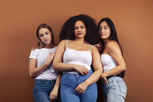 young pretty asian, caucasian, afro woman posing cheerful together on brown background, lifestyle diverse nationality people concept closeup