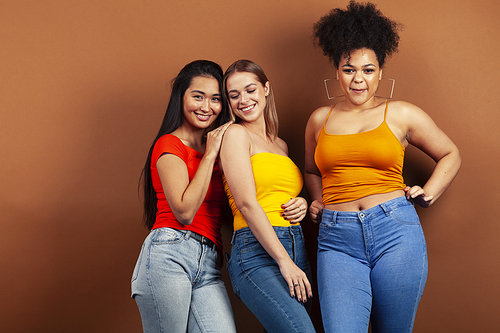 young pretty multiracial girls posing cheerful on brown background, lifestyle people concept closeup