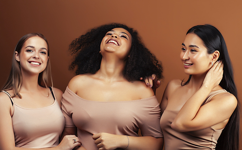 young pretty asian, caucasian, afro woman posing cheerful together on brown background, lifestyle diverse nationality people concept closeup