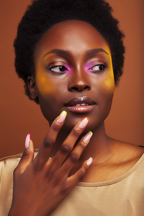 pretty young african american woman with curly hair posing cheerful gesturing on brown background, lifestyle people concept closeup