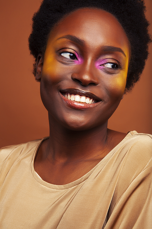 pretty young african american woman with curly hair posing cheerful gesturing on brown background, lifestyle people concept closeup