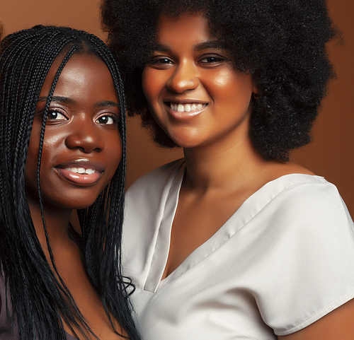 young pretty afro woman posing cheerful together on brown background, lifestyle diverse nationality people concept closeup