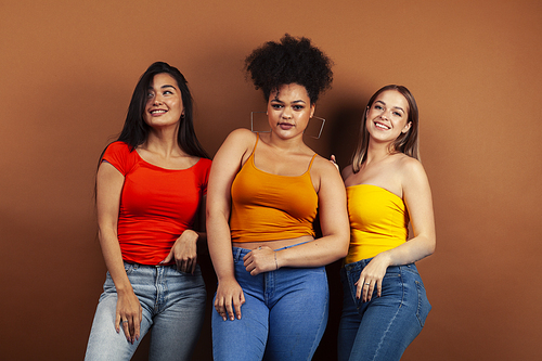 young pretty multiracial girls posing cheerful on brown background, lifestyle people concept closeup