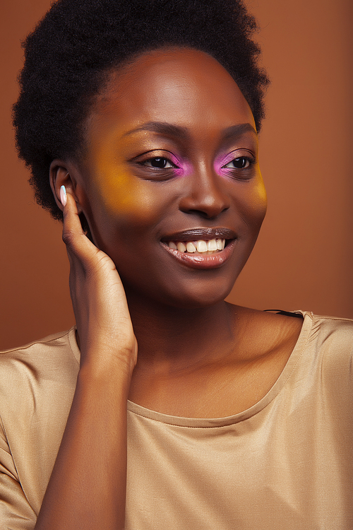 pretty young african american woman with curly hair posing cheerful gesturing on brown background, lifestyle people concept close up